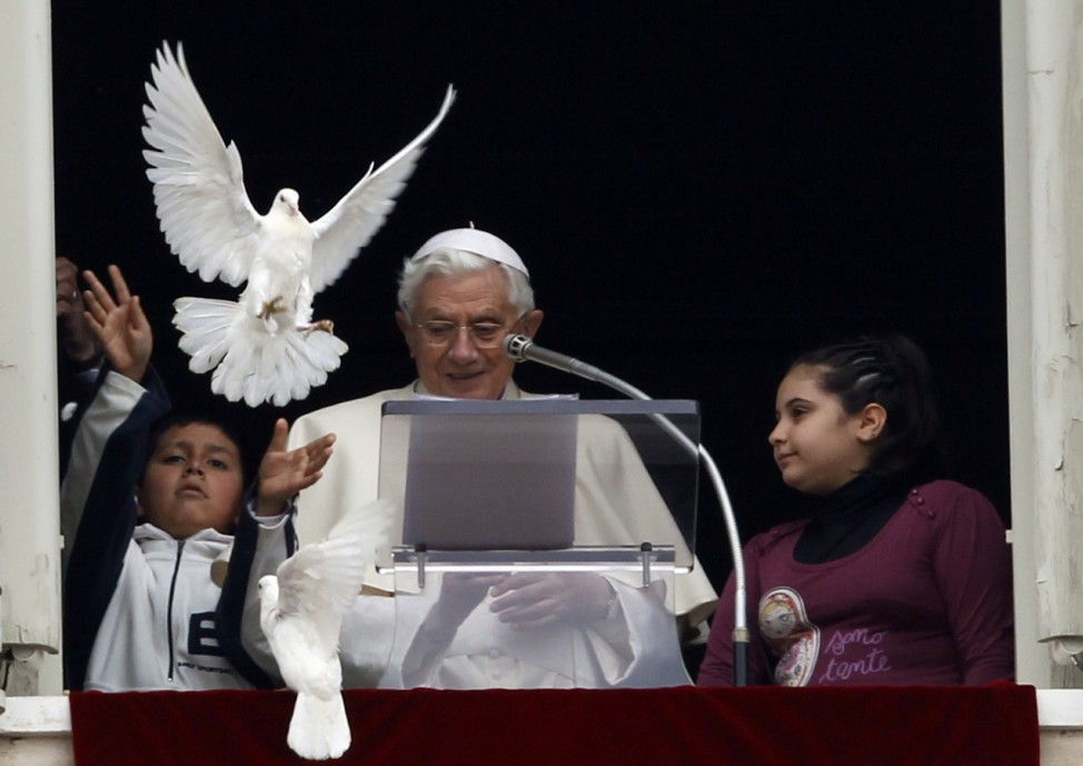Pope Benedict XVI reacts next to two young members of 'Azione Cattolica' as a dove is released from a window of his private apartments while he leads the Angelus prayer in Saint Peter's Square at the Vatican