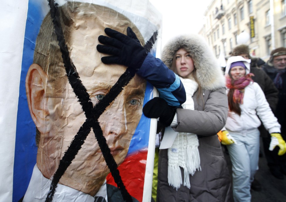 Demonstrators hold a crossed out portrait of Russian Prime Minister Vladimir Putin during a demonstration for fair elections in St.Petersburg