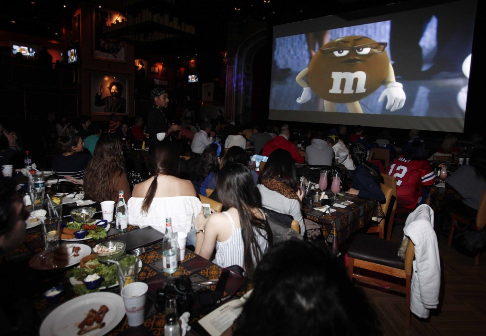 Fans watch an M&M's commercial at the Hard Rock Cafe in Times Square during the first quarter of the Super Bowl
