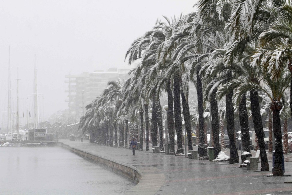 A woman walks along Palma de Mallorca's promenade during snowfall