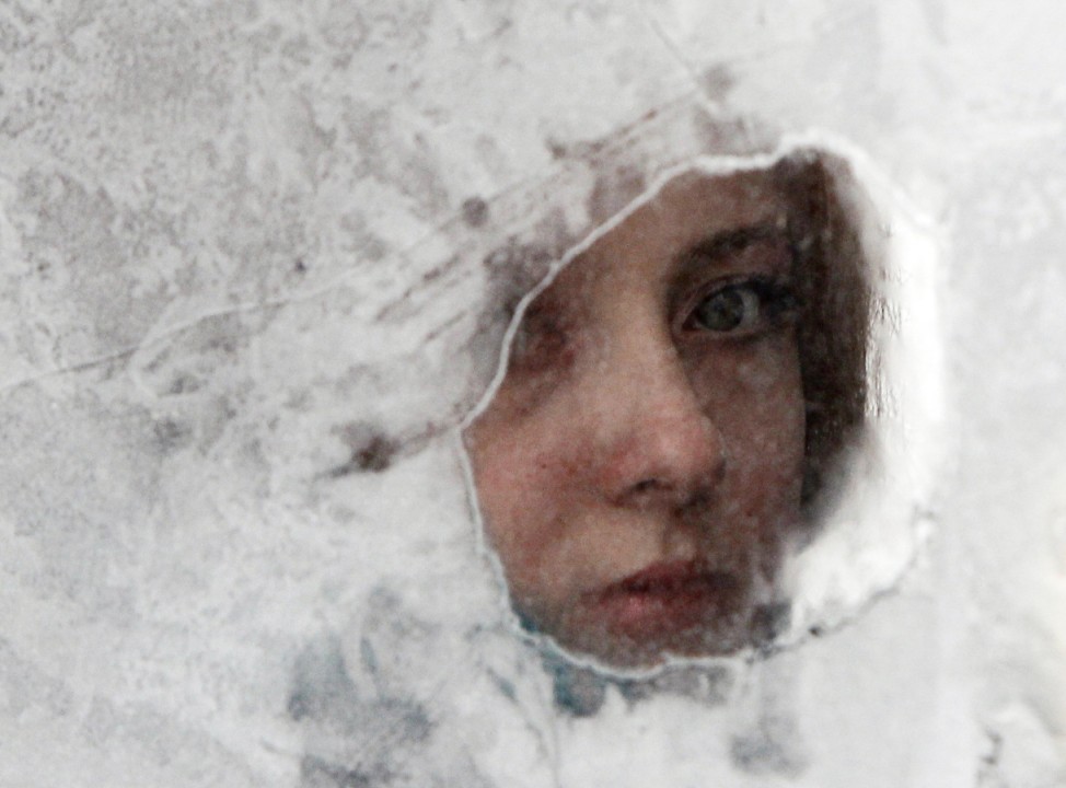A woman looks through a window of a minibus taxi covered with hoarfrost in Kiev