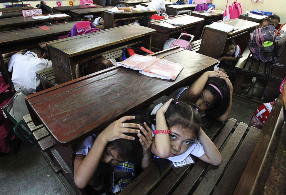 Students take cover under their desks during an earthquake drill at the Baclaran Elementary School Unit-1 in Paranaque city, metro Manila