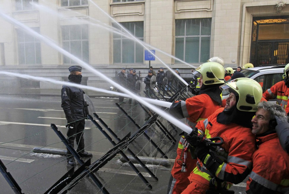 Firemen spray water outside a cabinet meeting during a demonstration in Brussels