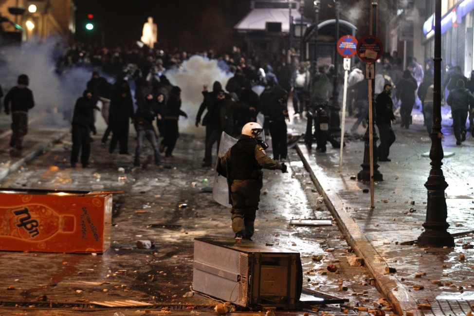 A riot policeman runs amidst stones and broken refrigerators during riots around Syntagma square in Athens