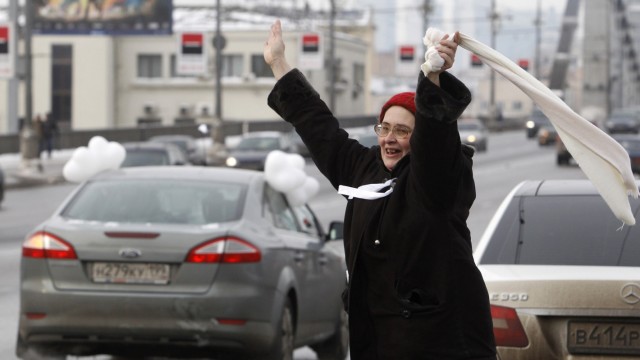 A woman greets participants of a car rally held to ask for a fair election, in Moscow