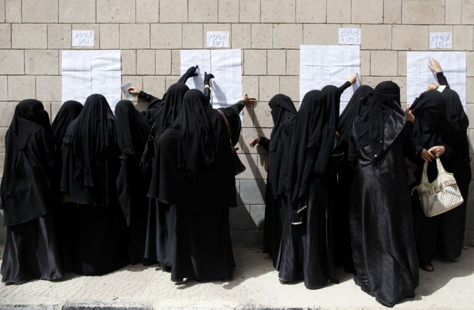Women check their names on a list before they vote at a polling station during presidential elections in Sanaa