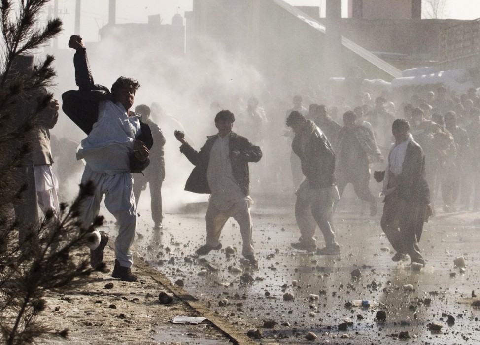 Afghan protesters throw rocks towards a water canon near a U.S. military base in Kabul