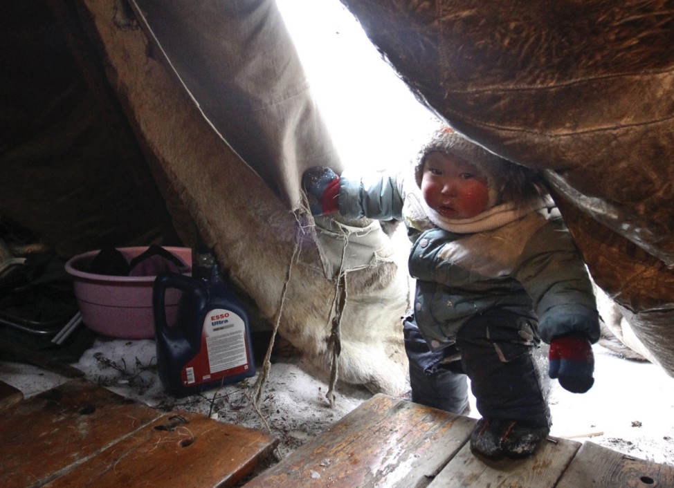 A Nenets boy enters a traditional tent called a chum, at a reindeer breeders' settlement in the Tundra region, 50 km (31 miles) from the north Russian town of Naryan-Mar