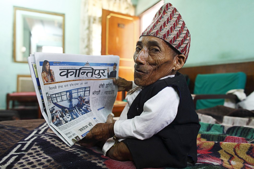 Dangi, who claims to be the world's shortest man, smiles as he sees his picture in a newspaper in Kathmandu