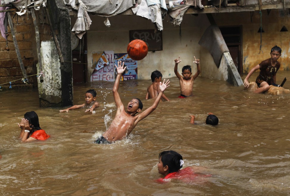 Children play with a ball during a flood near their house in Jakarta