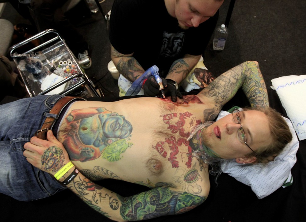 A tattoo artist works on a man during an international tattoo exhibition in Budapest