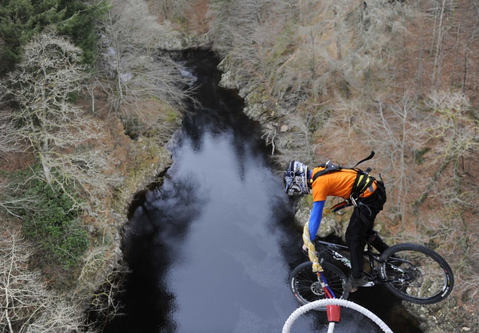Cyclist Adam Flint, attached to a bungee rope, pedals off the Garry Bridge near Pitlochry, in Scotland