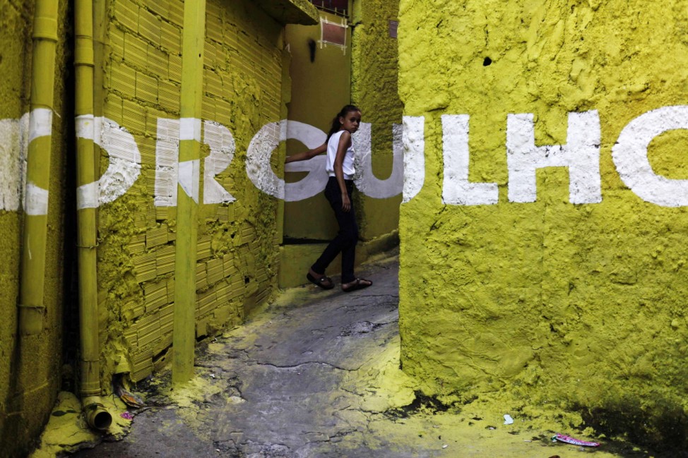 A woman leaves her house next to the word 'Pride' in an alley (viela), in the Brasilandia favela of Sao Paulo