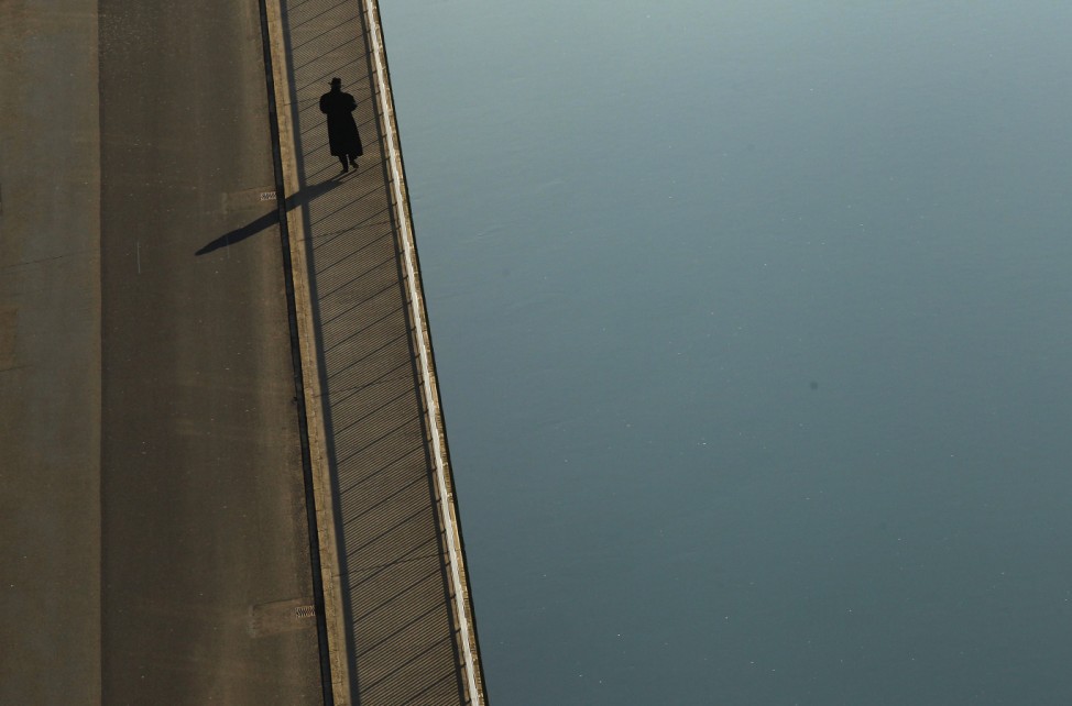 Man casts shadow as he walks along the shore of river Aare in Bern
