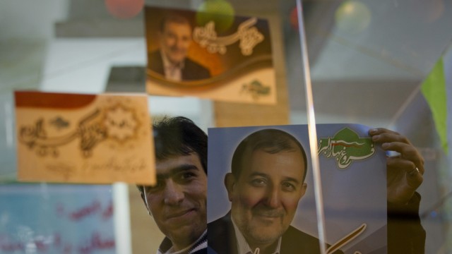 A campaign volunteer shows a campaign poster at his campaign headquarters in Karaj