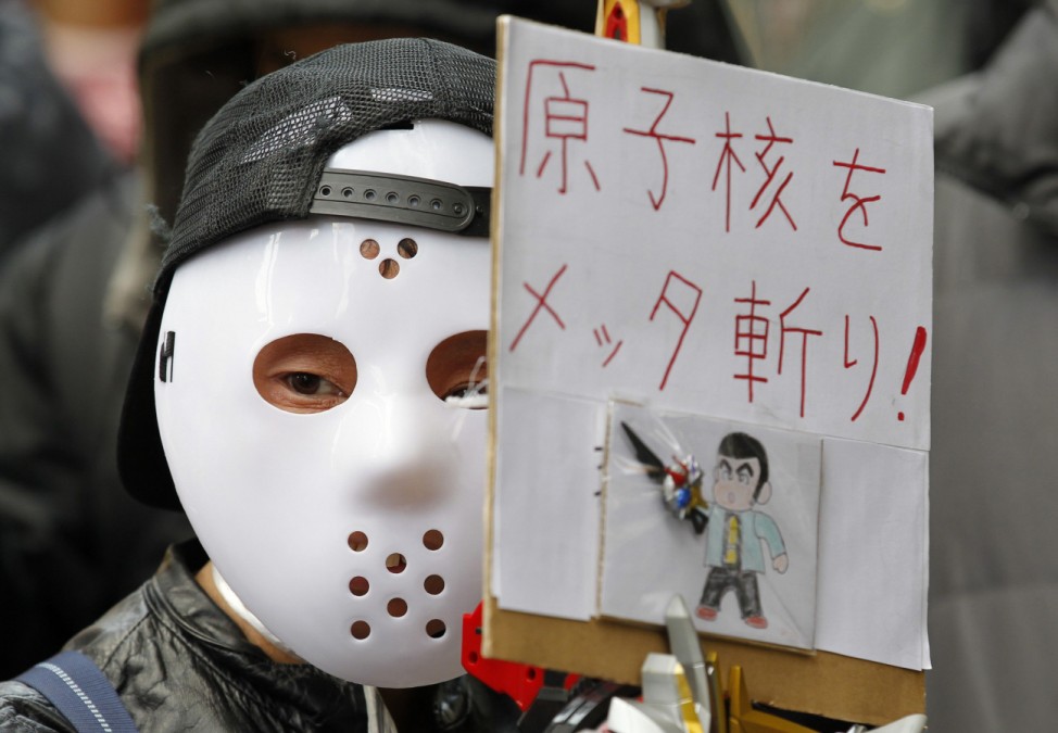 A protester wearing a mask holds a sign at a rally demanding for the abolition of nuclear power in Tokyo