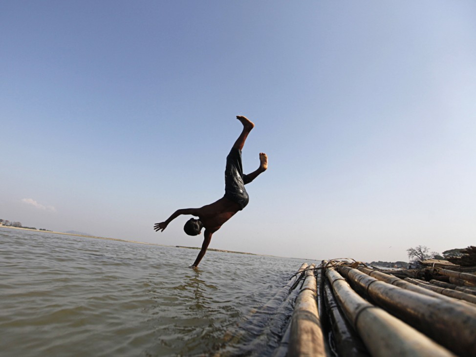 A boy dives into the water to take a shower along the bank of the Irrawaddy river near Mingun village in Sagaing, southwest of Mandalay