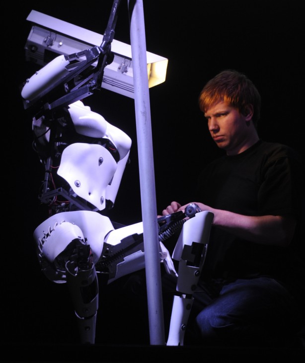 A worker adjusts a pole dancing robot during preparations at the CeBit computer fair in Hanover.