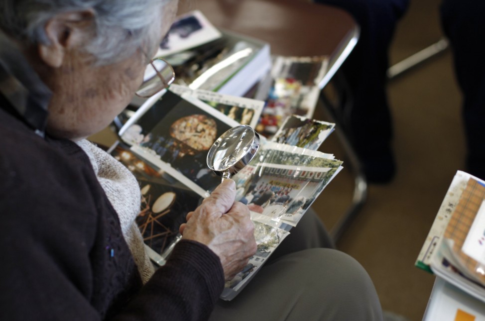 A tsunami victim looks through albums for her photographs, which were washed away by the March 11, 2011 earthquake and tsunami, at an assembly house in temporary compounds in Ofunato