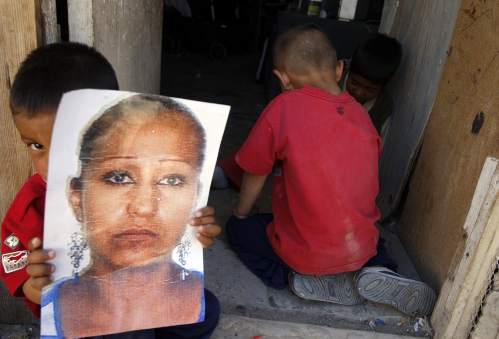 A boy holds a photograph of his mother, who has been missing since May 26, 2011, outside his home in Ciudad Juarez