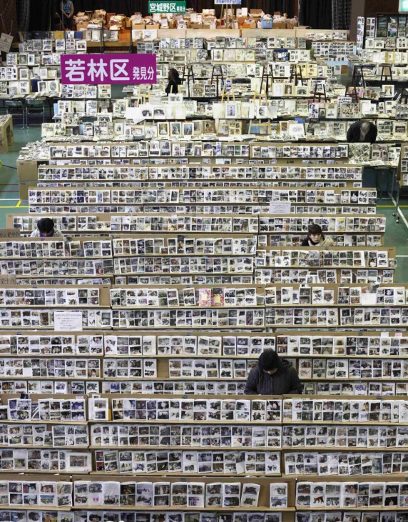 People look for their photographs at a collection centre for items in Sendai, Miyagi prefecture