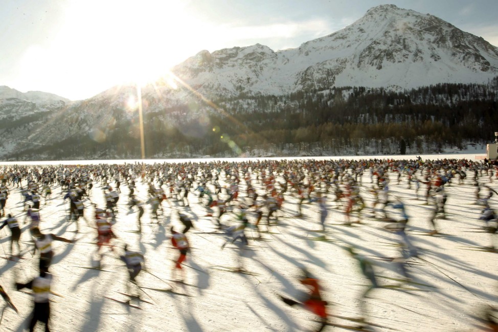 The first wave of cross-country skiers starts on the frozen Lake Sils near the village of Maloja