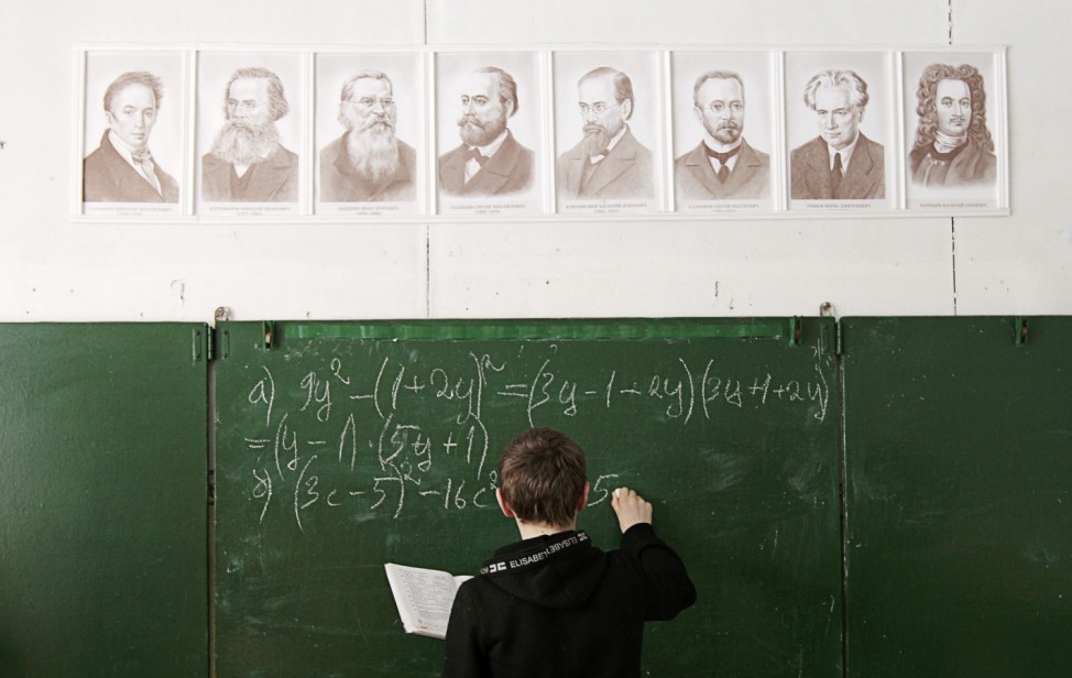 A pupil writes on the blackboard as he attends a mathematics lesson at a local school based in the remote Russian village of Bolshie Khutora
