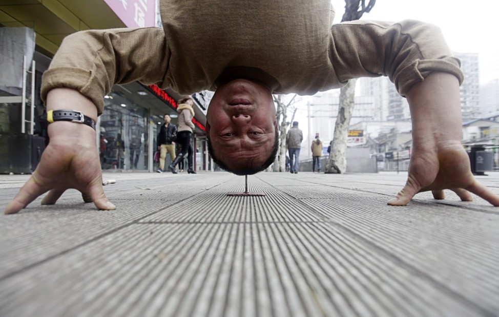Xu Tiancheng, 56, uses 'Qi Gong' or 'Internal Energy' to practice a headstand on a flat nail on a pedestrian street in Wuhan