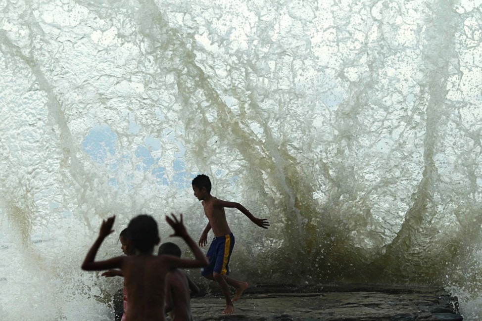 An East Timorese child runs as sea water hits the wall on Dili beach
