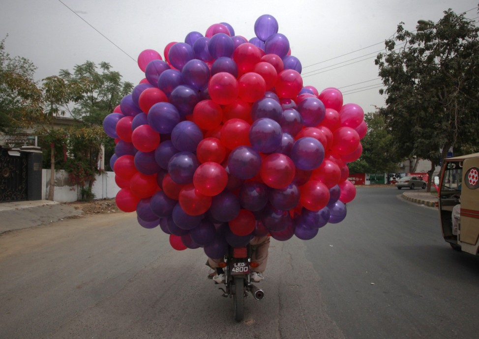 Men transport balloons on a motorbike in Lahore