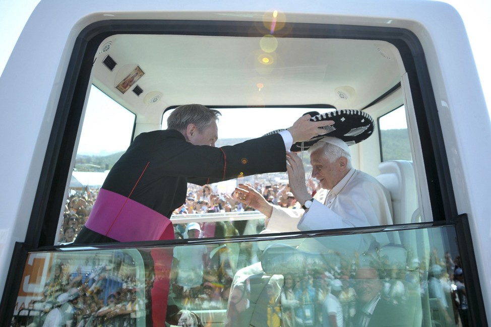 Pope Benedict XVI is helped as he wears a traditional Mexican hat while being driven through the crowd before officiating mass in Silao