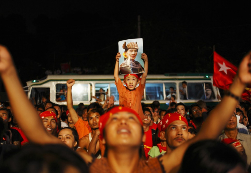 A child holds up a portrait of pro-democracy leader Suu Kyi, as election results are revealed on a screen in front of the head office of the NLD in Yangon