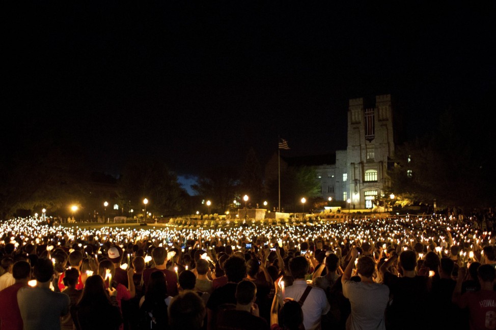 Members of the community hold up candles as they listen to taps being played during a commemoration and candlelight vigil on the campus of Virginia Tech in Blacksburg
