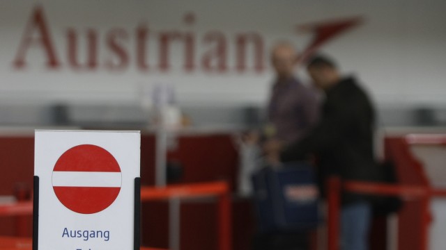 The logo of Austrian airline is seen behind an exit sign at a check-in desk at Vienna International Airport