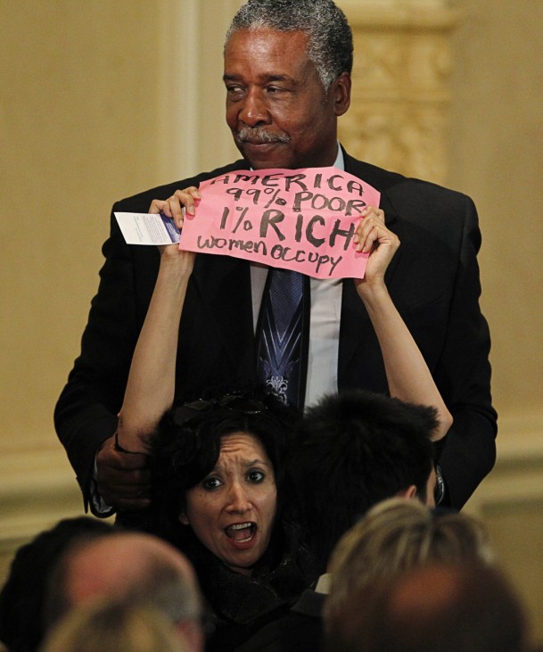 A demonstrator affiliated with the Occupy Wall Street movement is detained by security following a speech by Treasury Secretary Timothy Geithner at the Commonwealth Club at the Mark Hopkins Hotel in San Francisco