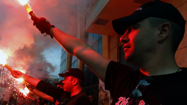 Members of the Greek extreme right Golden Dawn party hold red flares outside the town hall of Perama town
