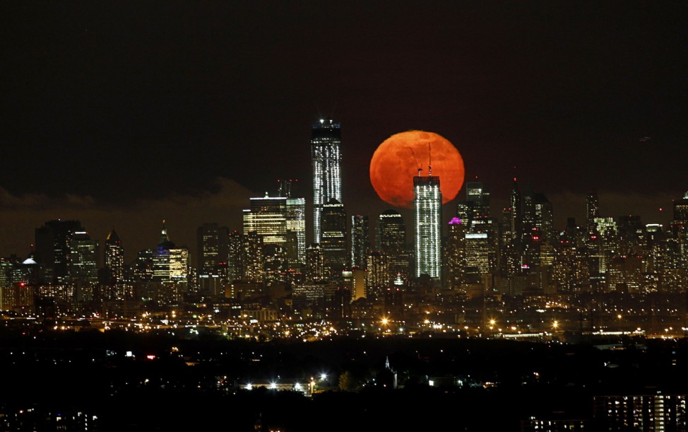 A full moon as seen from West Orange, New Jersey, rises over the skyline of Lower Manhattan and One World Trade Center in New York