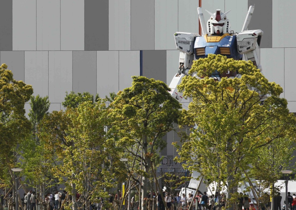 Full-size model of Japan's robot animation character 'Gundam' stands in front of a shopping mall behind trees in Tokyo