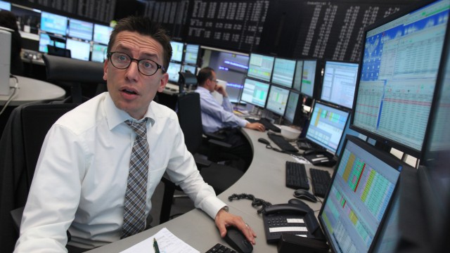 A trader reacts at his desk in front of the DAX board at the Frankfurt stock exchange