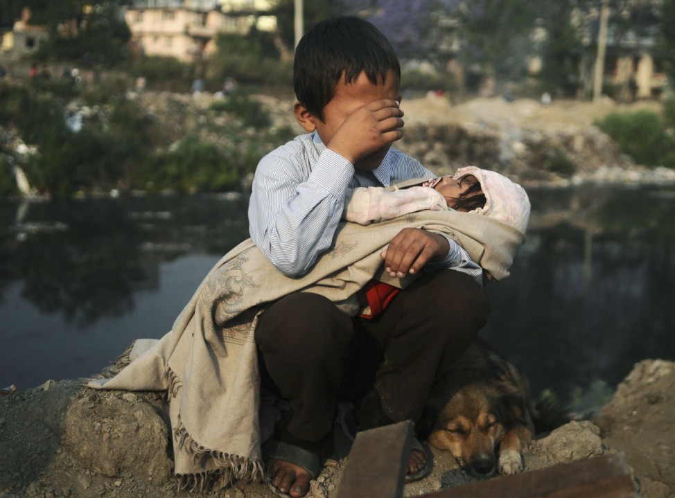 A boy cries as he holds his sister in his lap after a confrontation with squatters and police personnel, who arrived to demolish houses that were built illegally, in Kathmandu