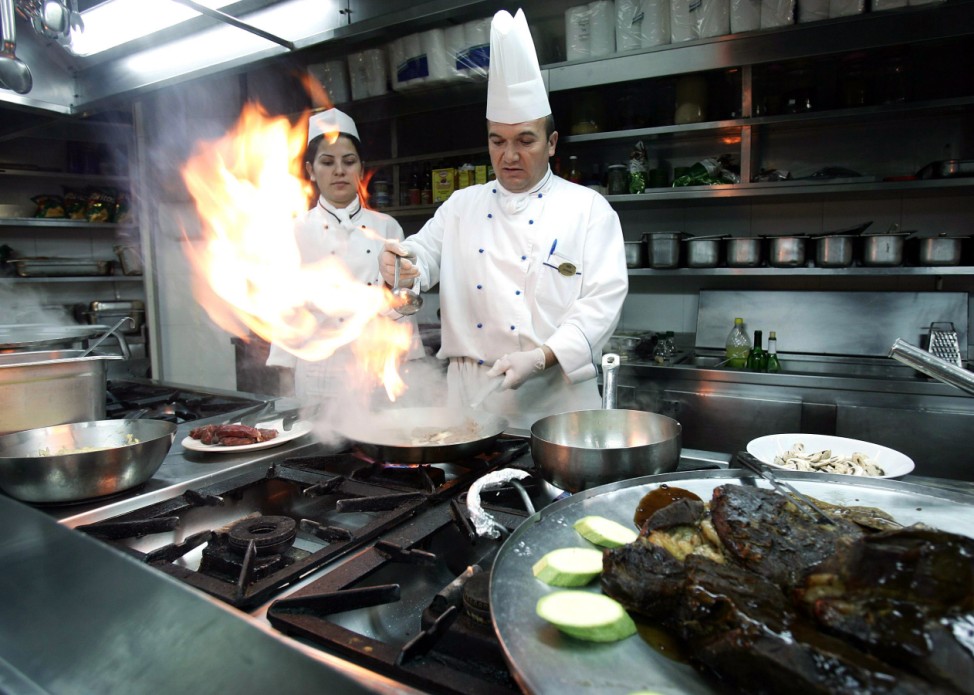 Turkish cook prepares beef steak on fire in restaurant in Mediterranean Turkish city of Antalya