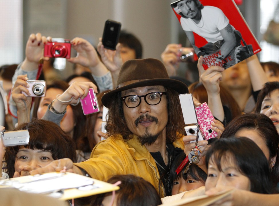 A Japanese impersonator of actor Depp reaches out to receive an autograph upon his arrival at Narita international airport in Narita, east of Tokyo