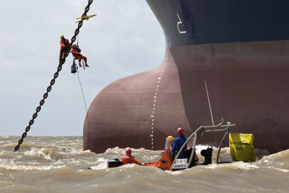 A Greenpeace activist climbs up the anchor chain of the Bahamas-flagged Clipper Hope cargo ship in Sao Luis