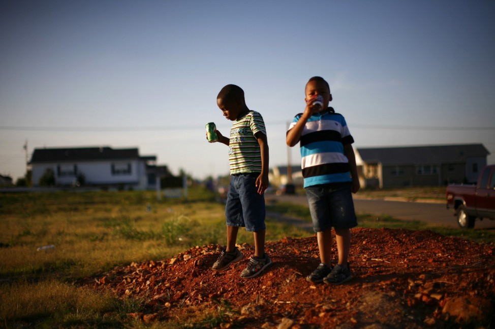Boys stand on an empty lot where a house once stood in Joplin