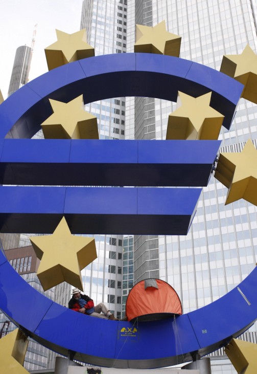 A demonstrator sits in the euro sculpture as he waits for police to clear the camp of occupy protestors in front of the European Central Bank (ECB) in Frankfurt
