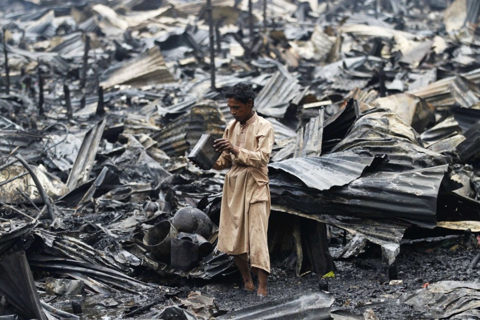 A man salvages his belongings after a fire in a slum at Shyamoli in Dhaka
