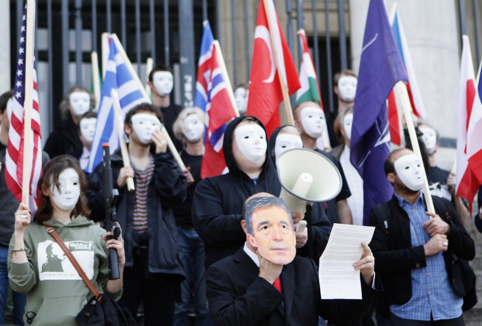 A man wears a mask of NATO Secretary General Rasmussen as peace activists wearing masks gather for a flashmob during a protest against NATO, in front of the Stock Exchange in Brussels