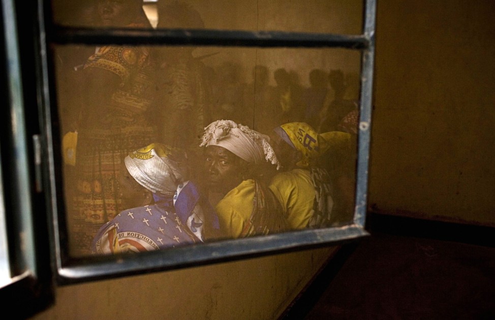 Members of Congolese Women's Association are reflected in a window during their meeting in the town of Rutshuru