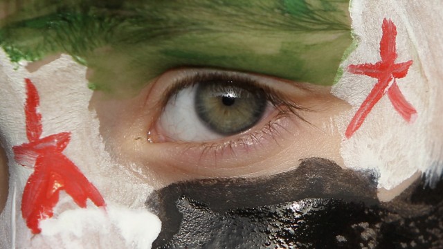 A boy with his face painted in the colours of the Syrian opposition flag takes part in a demonstration in Amman