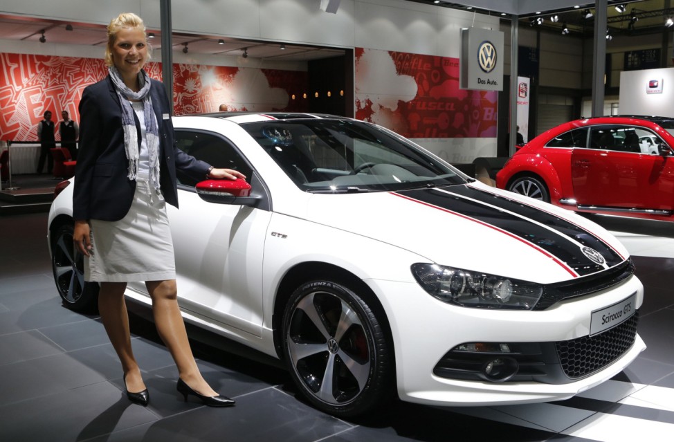 A model poses next to a Volkswagen Scirocco GTS car during a press preview day at the AMI Auto Show in Leipzig